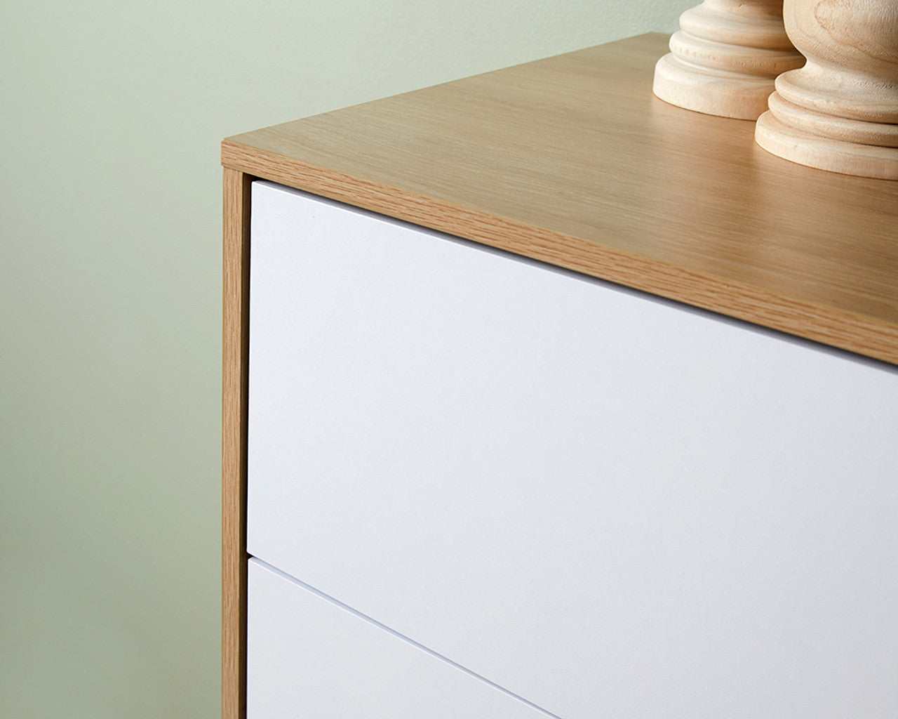 Close-up view of coastal tallboy chest of drawers with white drawer fronts and natural wood top finish