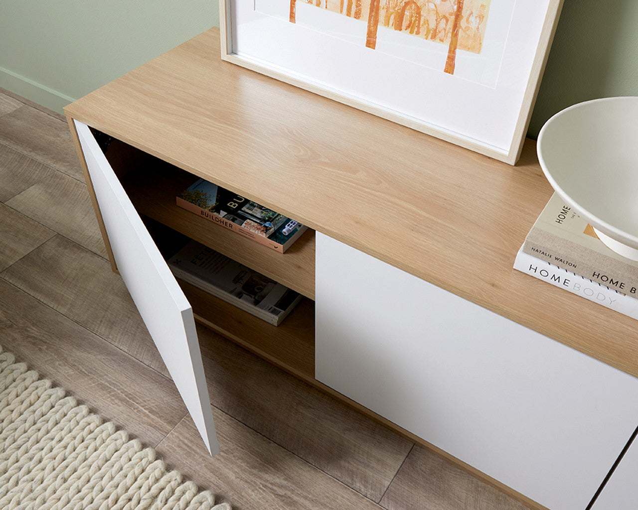 Imperial Homes coastal TV unit with white doors and wood top showing open storage space with books