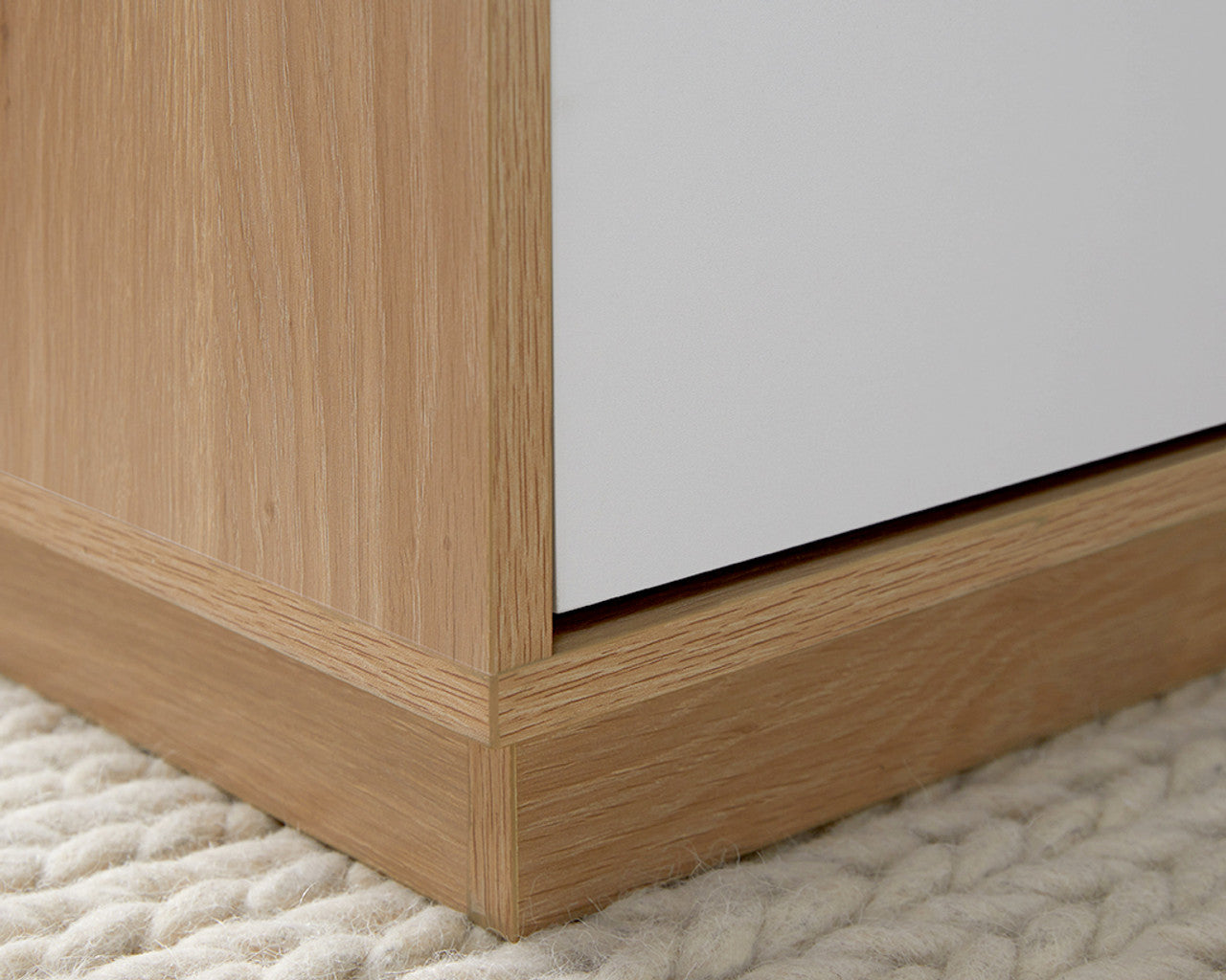 Close-up of modern minimalist coffee table corner with wood grain texture on a soft woven rug