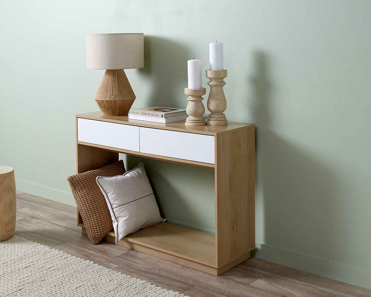 Imperial Homes coastal console table in light wood with white drawers styled with lamp, candles, and pillows