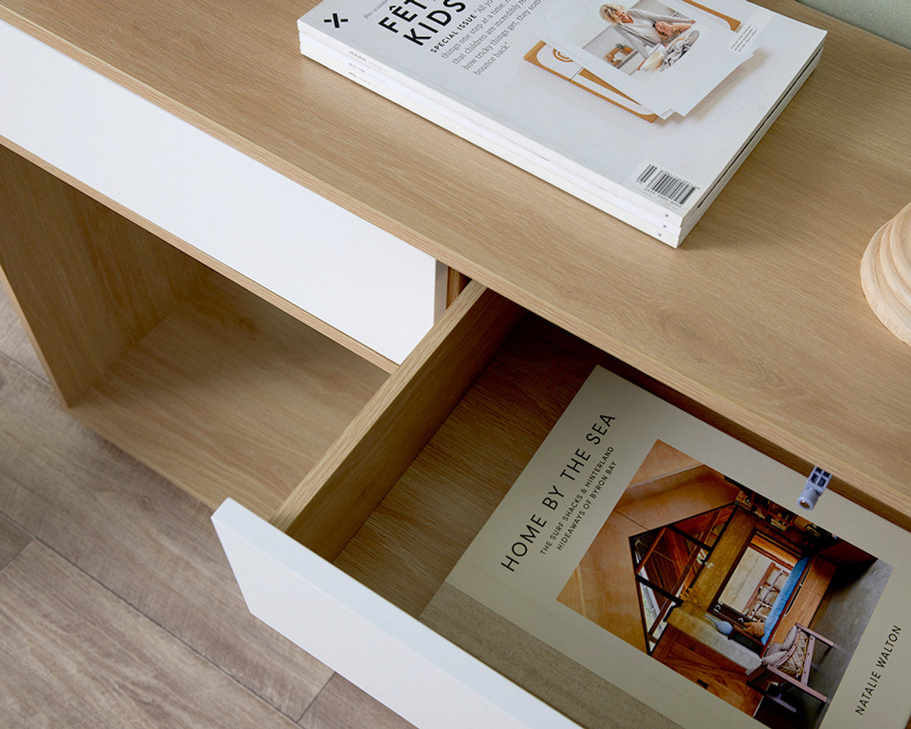 Imperial Homes coastal console table with wood top and white drawers holding books and magazines