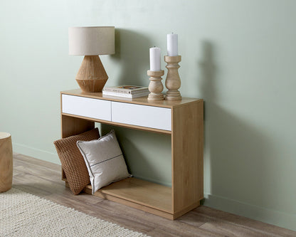 Imperial Homes coastal console table in light wood with white drawers styled with lamp, candles, and pillows