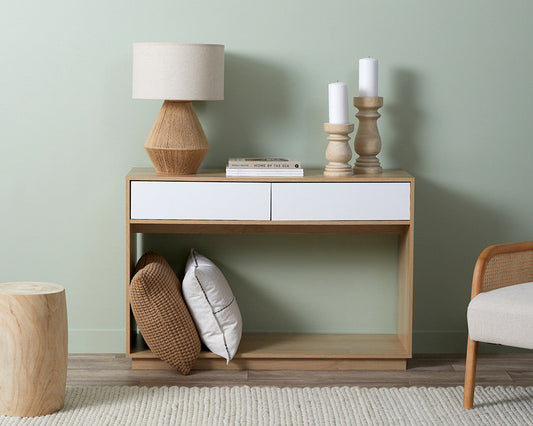 Coastal console table by Imperial Homes with two white drawers styled with lamp, candles, and decorative pillows